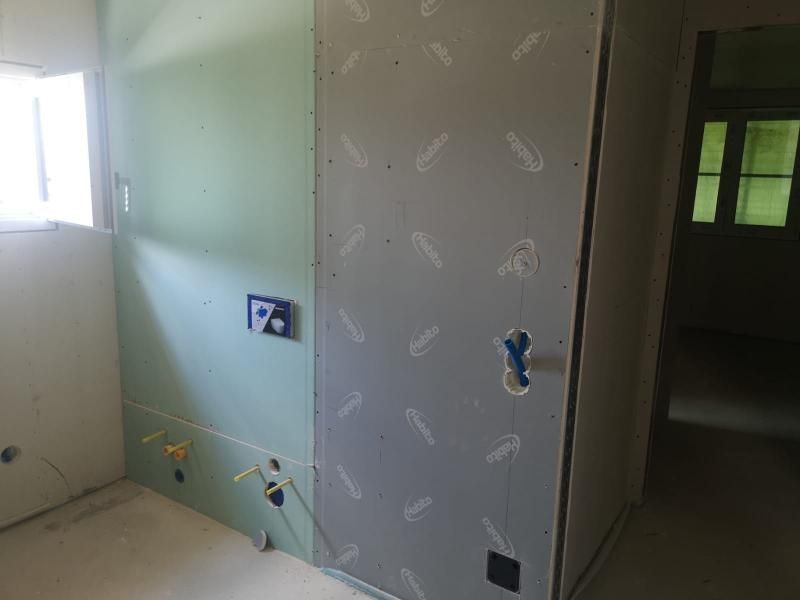 Parete interna con impianto idraulico in una stanza in costruzione. Cartongesso verde e grigio.