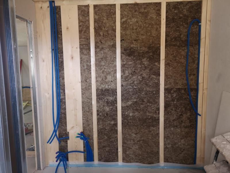 Una stanza con una parete di legno e da essa escono tubi blu.