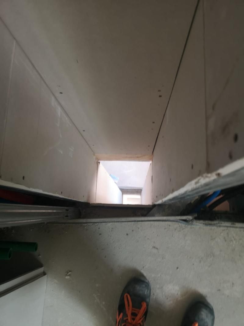 Uno sguardo verso il basso, in uno stretto condotto rettangolare. Pareti di cemento, non finite.