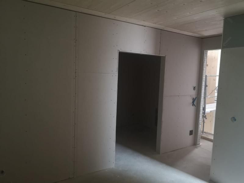 Vista interna di una stanza in costruzione con pareti in cartongesso e stipite della porta.