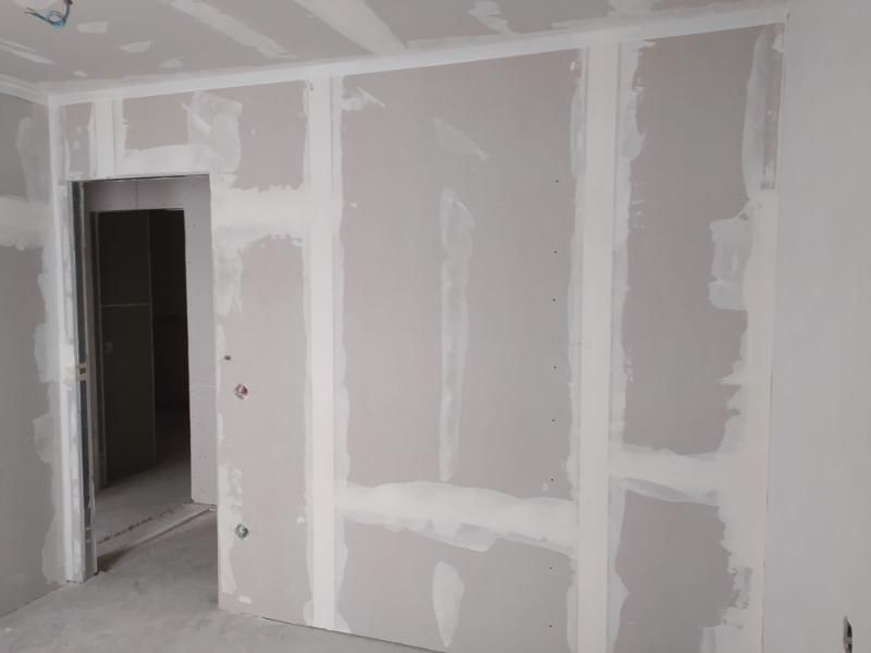 Una stanza con pareti in cartongesso e una porta.