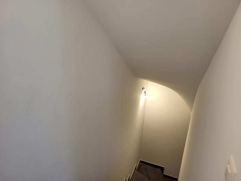 Uno stretto corridoio con scale e una luce sul soffitto.