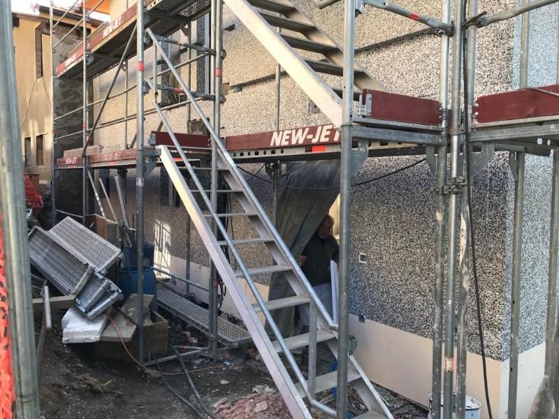 Un uomo è in piedi su una rampa di scale di fronte a un edificio.