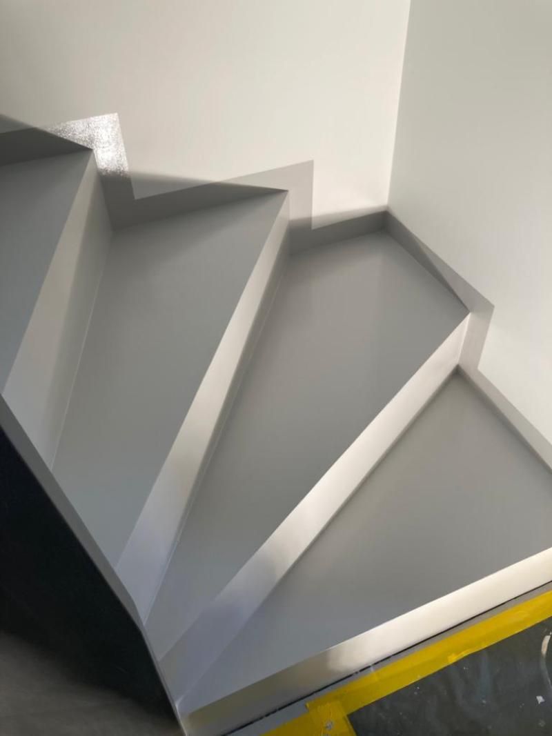 Scale grigie con finiture bianche su pareti bianche.