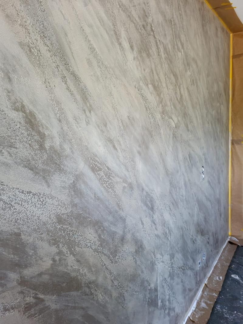 Parete grigia e bianca con effetto pennellate, angolo di una stanza.