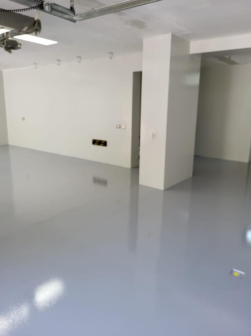 Stanza vuota con pavimento grigio chiaro e pareti bianche.