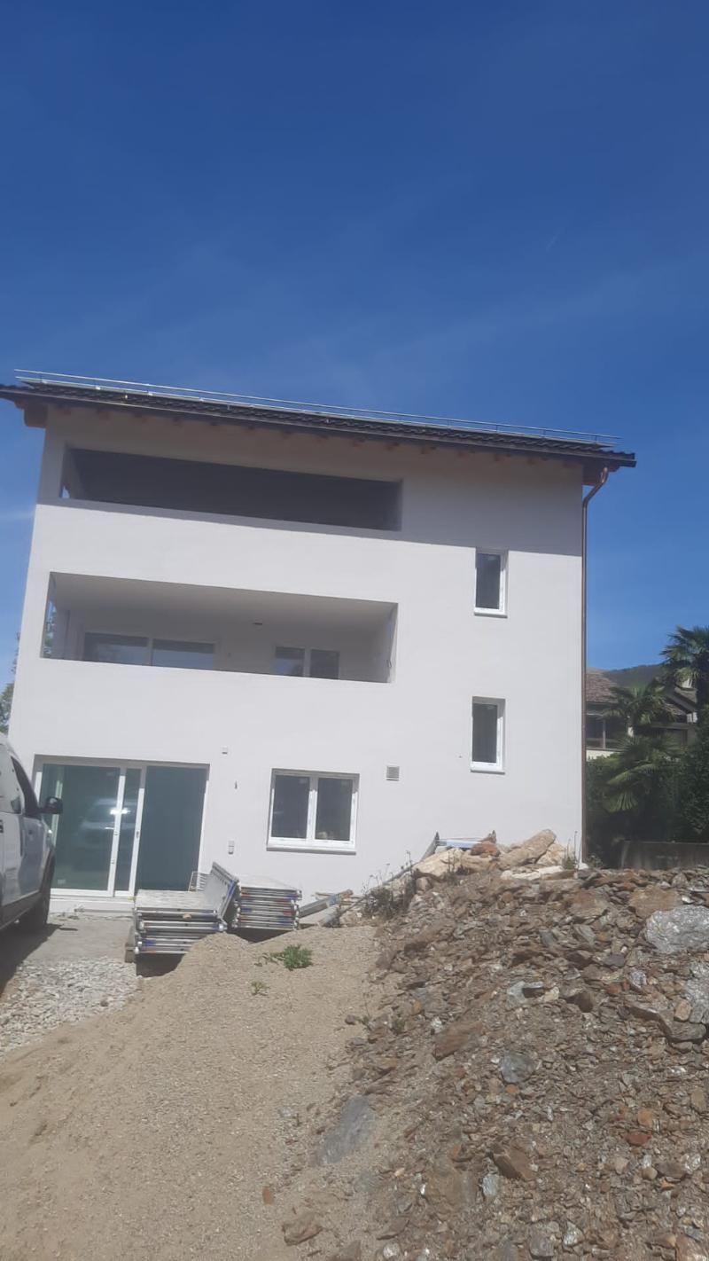 In mezzo a un campo sterrato si sta costruendo una grande casa bianca.