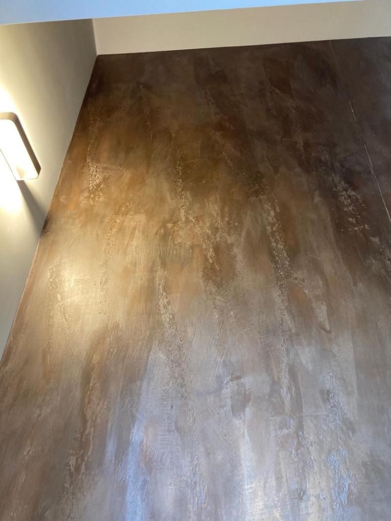 Una stanza con il pavimento marrone e una luce sul muro.