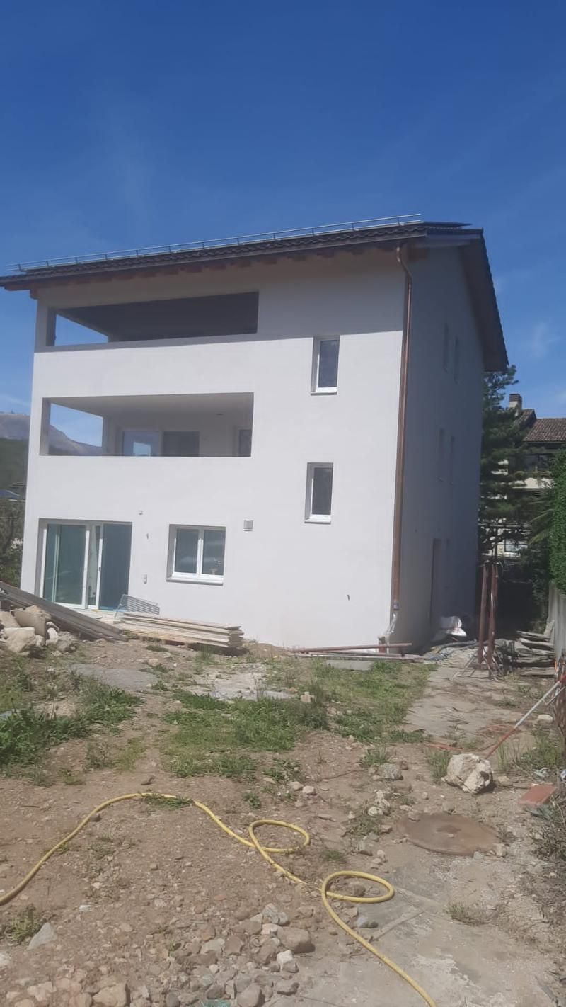 In mezzo a un campo sterrato si sta costruendo una grande casa bianca.