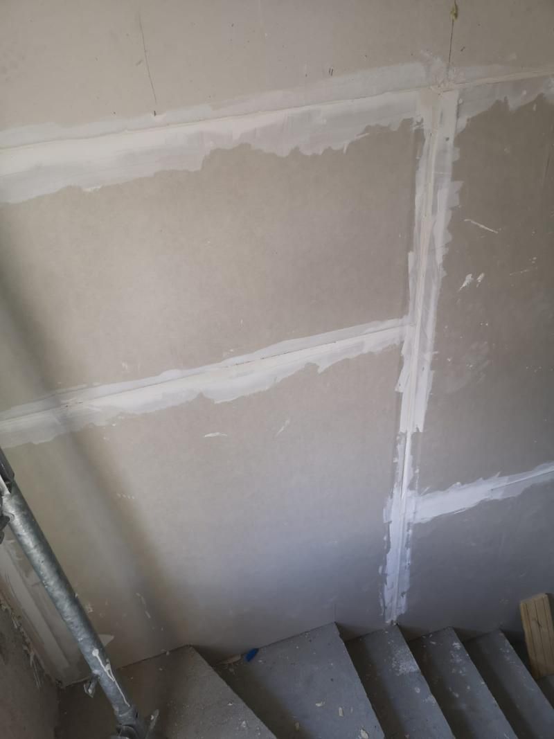 Un primo piano di un muro con una scala sullo sfondo.