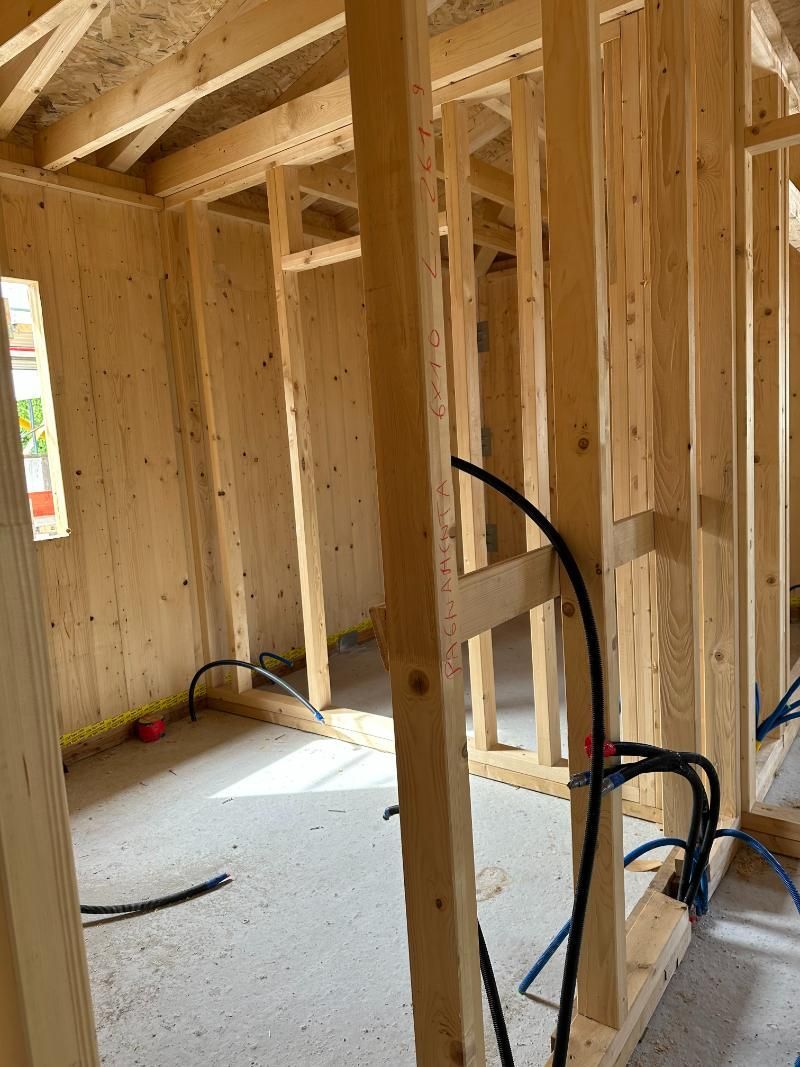 Una stanza di una casa in costruzione con travi in ​​legno e cavi elettrici.