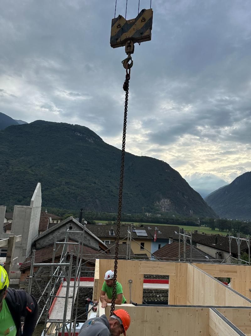 Un uomo viene sollevato da una gru in cima a un edificio.