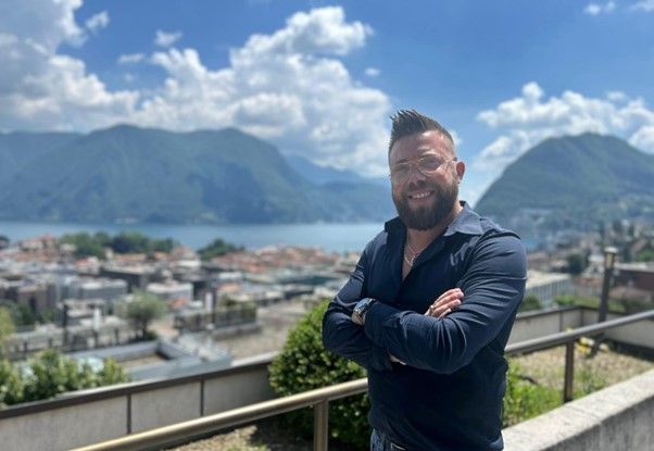 Due uomini sono in piedi uno accanto all'altro in una stanza con in mano dei trofei.