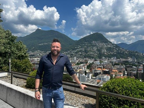 Due uomini sono in piedi uno accanto all'altro in una stanza con in mano dei trofei.