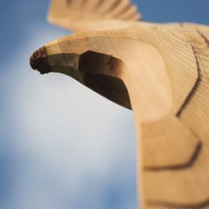 Eine Nahaufnahme einer Holzskulptur eines Vogels, der am Himmel fliegt.