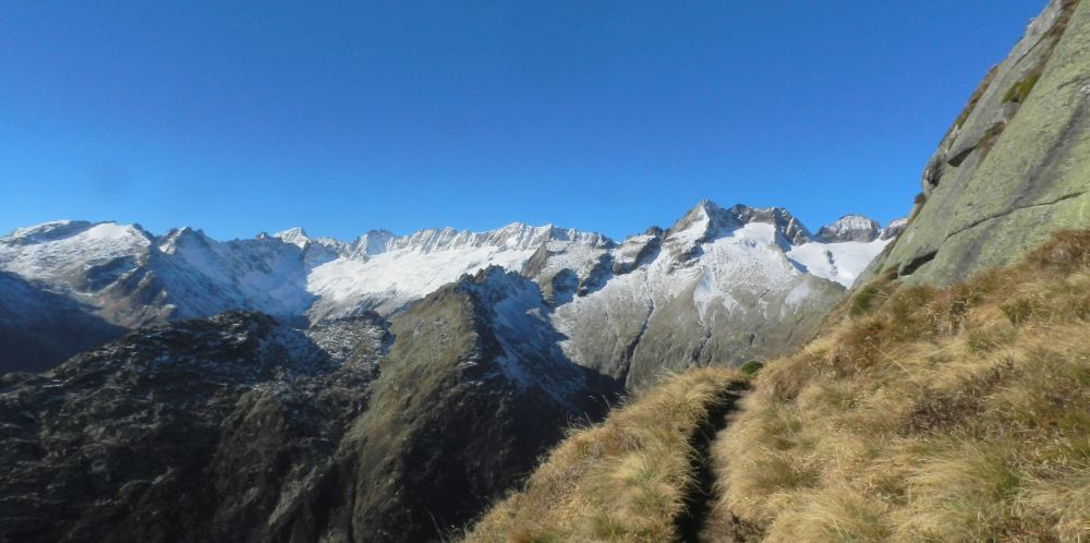 Eine Bergkette mit Schnee auf den Gipfeln und einem Pfad im Vordergrund.