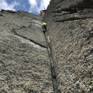 Eine Person klettert eine Felswand hinauf.