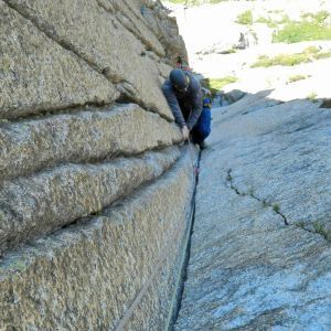 Ein Mann klettert mit einem Seil eine Felswand hinauf.