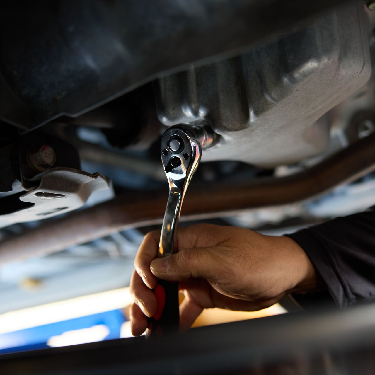 On utilise un outil sur un élément en dessous d'une voiture