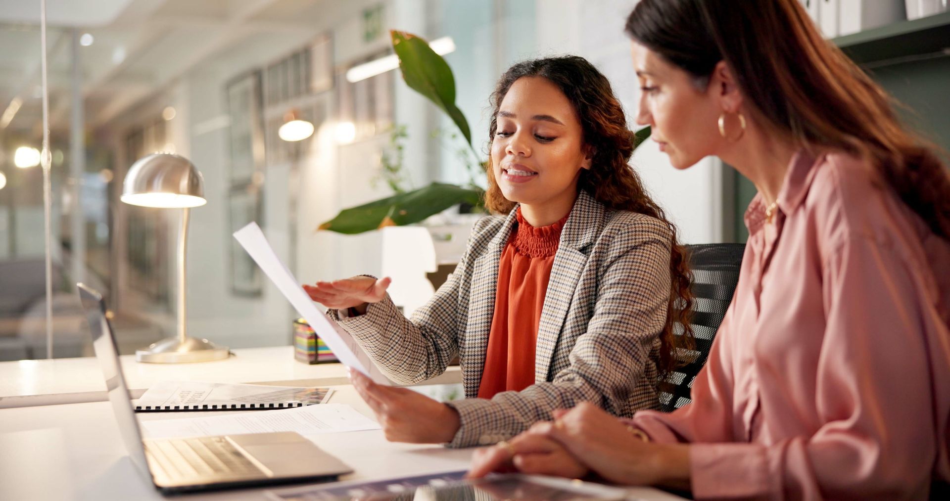 Deux femmes examinent des documents dans un bureau moderne.