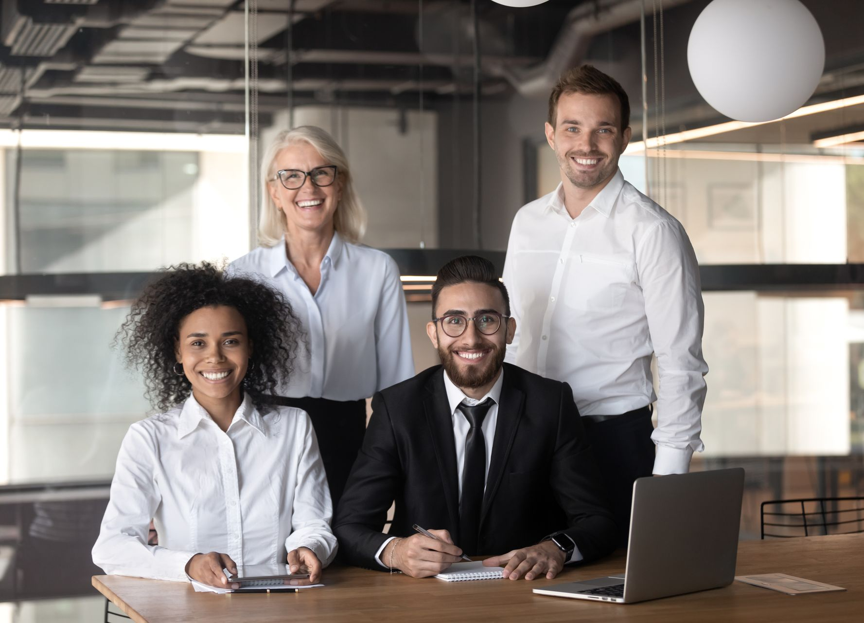 Quatre professionnels souriants posent autour d'une table dans un bureau.