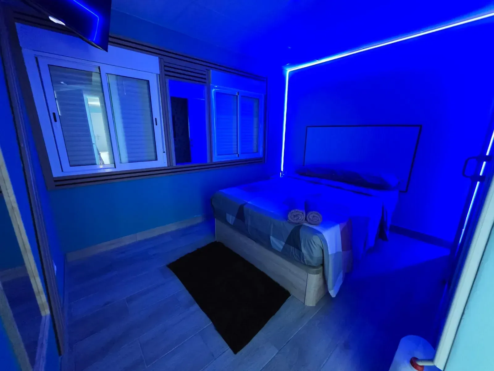 Un dormitorio con una cama y luces azules en las paredes.