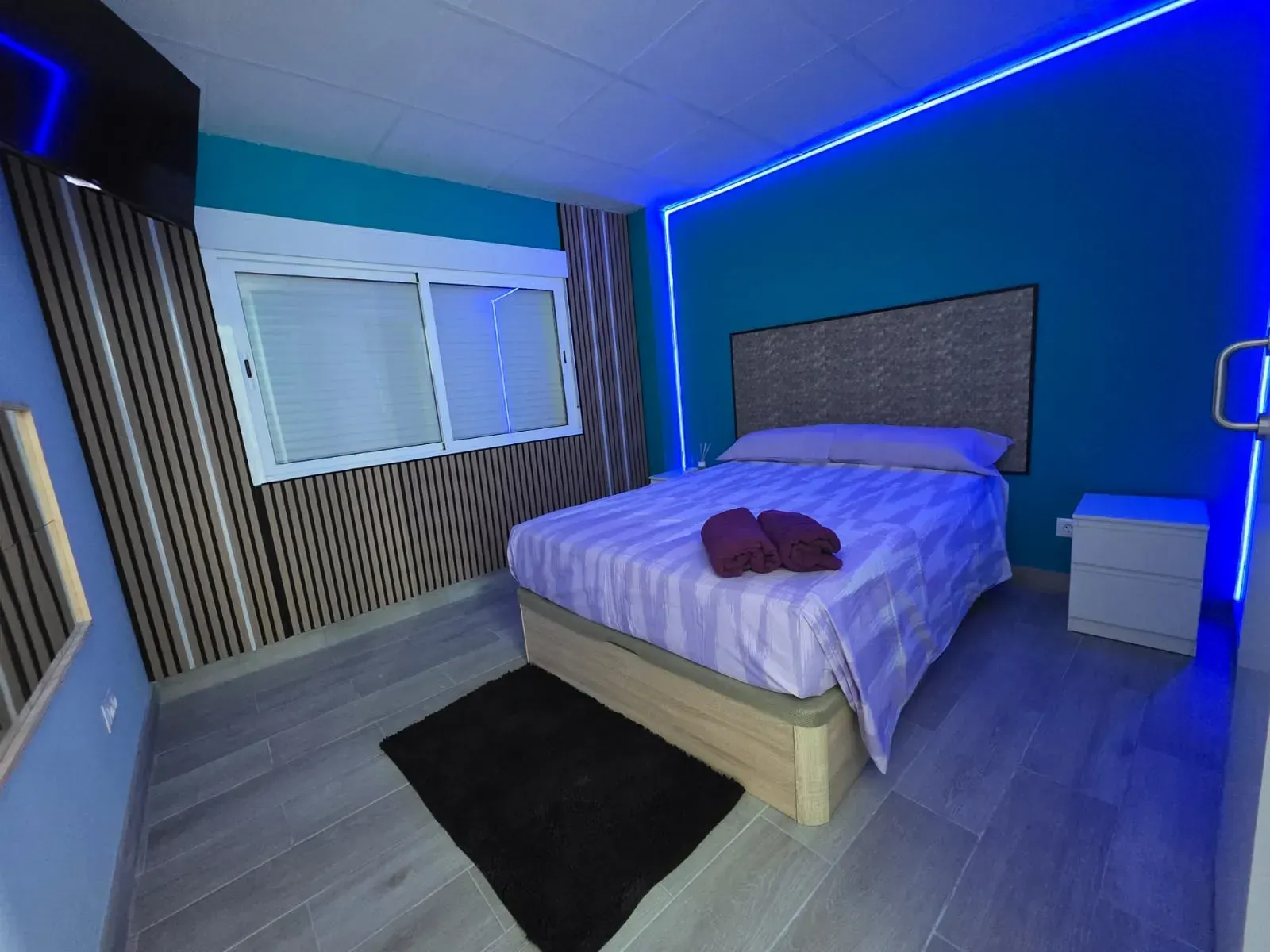 Un dormitorio con cama, mesita de noche y televisión.