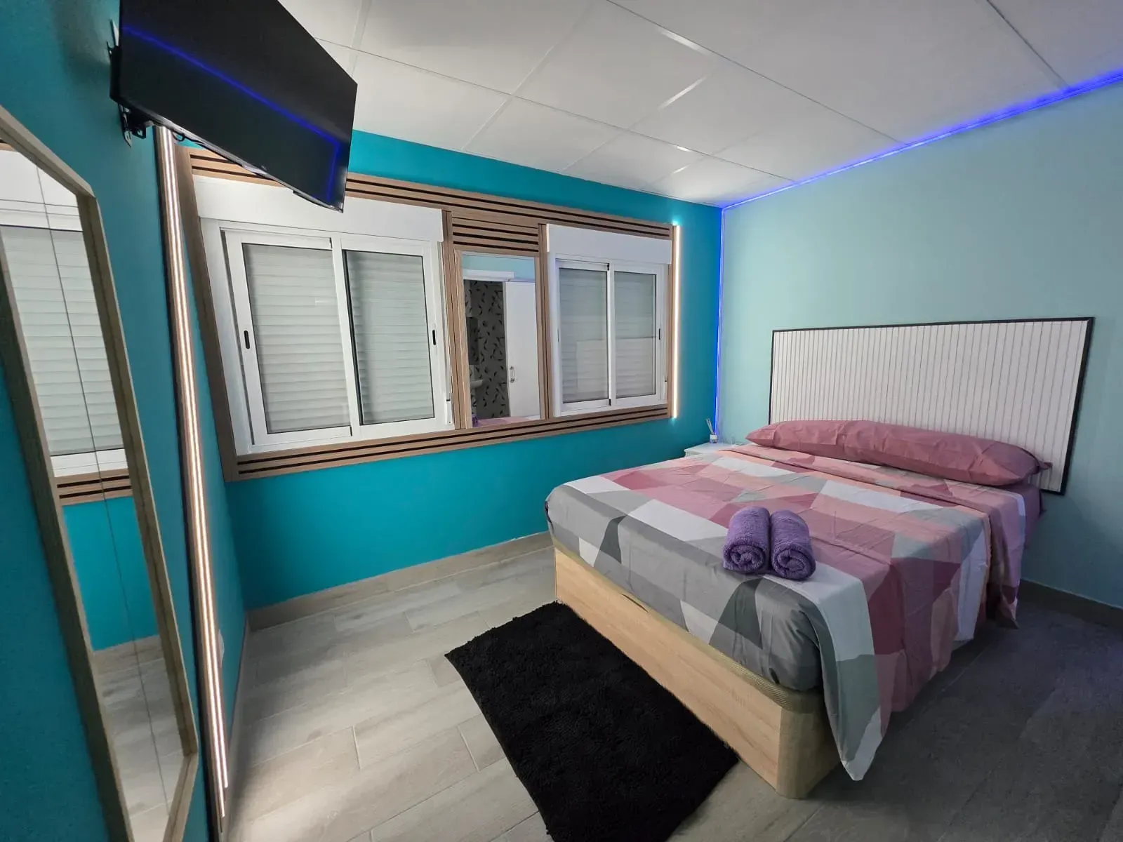 Un dormitorio con una cama y un televisor en la pared.