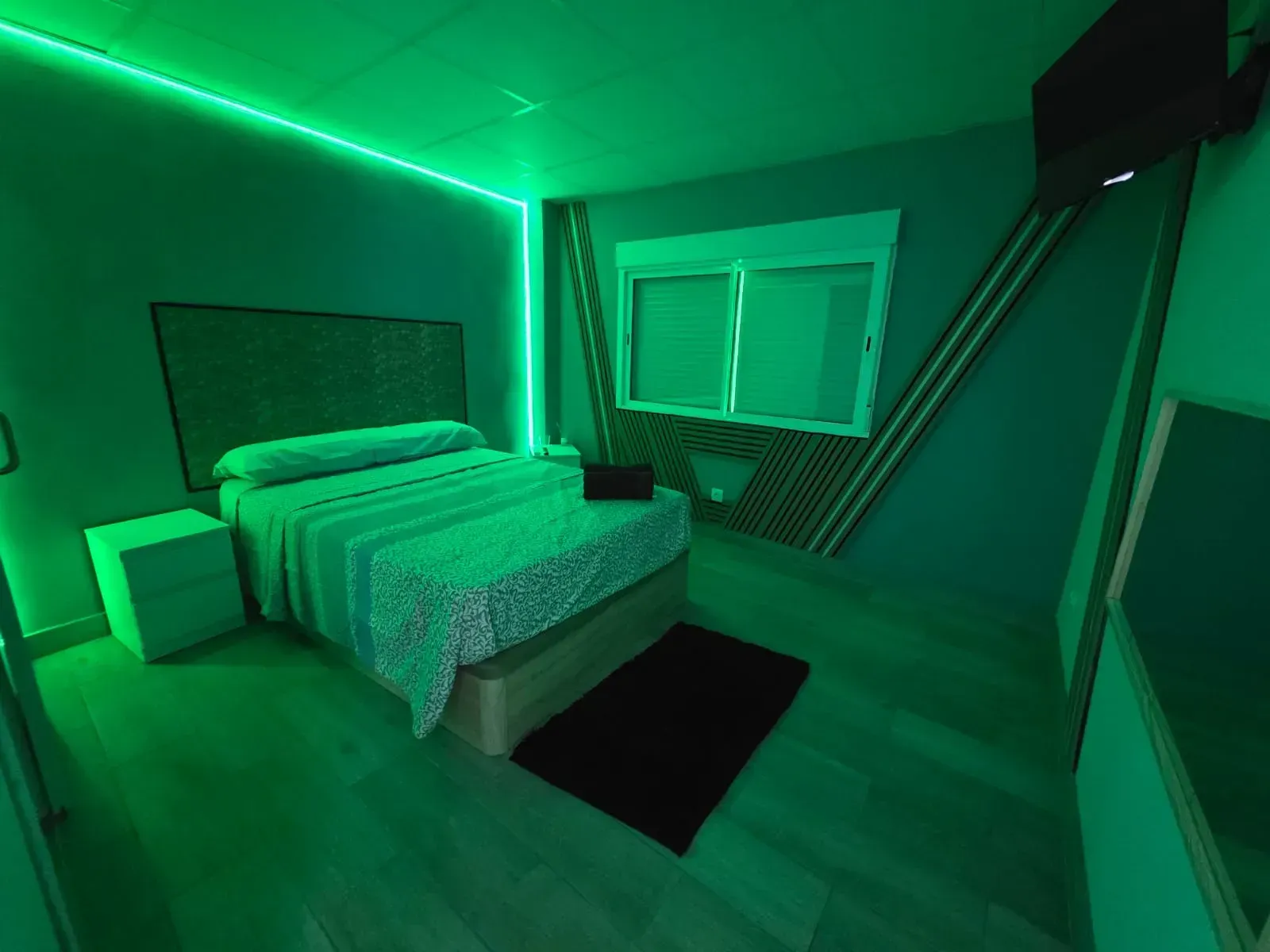 Un dormitorio con una cama y luces verdes en el techo.