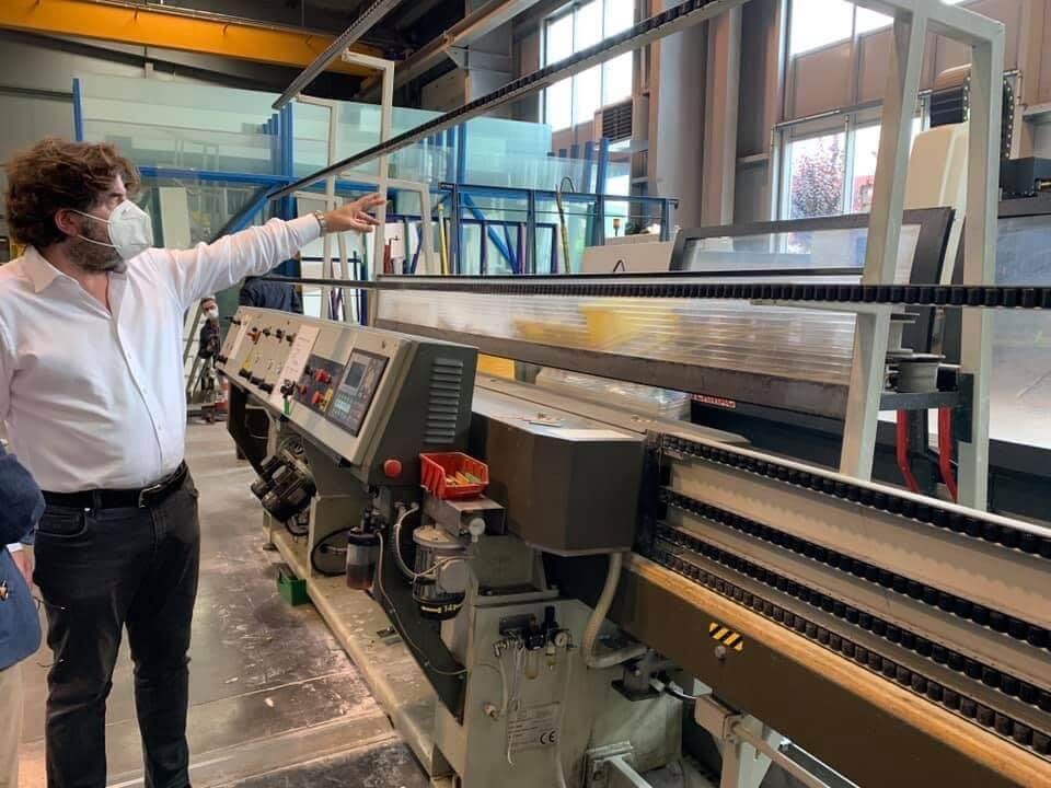Une personne portant un masque facial désigne une machine dans une usine ou un atelier.