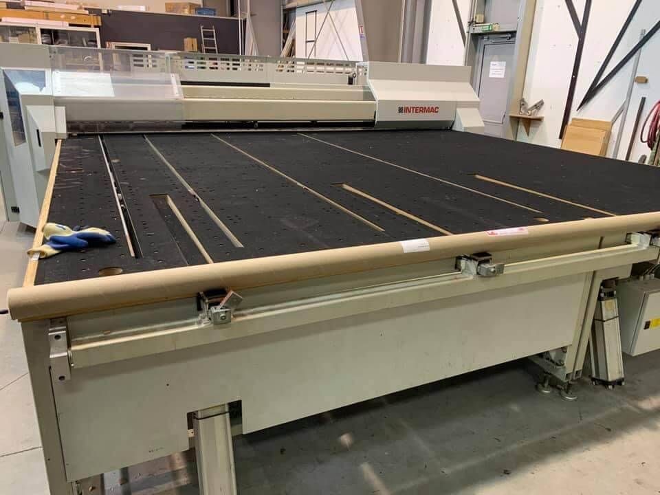Une grande scie à poutre industrielle pour la découpe de panneaux, installée dans un atelier d'entrepôt.