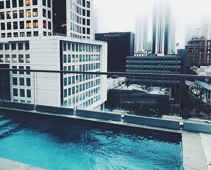 Une piscine à débordement sur le toit offre une vue imprenable sur la silhouette brumeuse de la ville et ses immeubles de bureaux modernes aux façades de verre.
