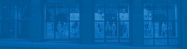 Une devanture de magasin avec de grandes vitrines présentant des mannequins, teintées d'un filtre bleu monochrome.