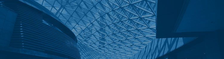 L'intérieur d'un bâtiment moderne avec un grand plafond en verre aux formes géométriques complexes, baigné d'un filtre bleu monochrome.