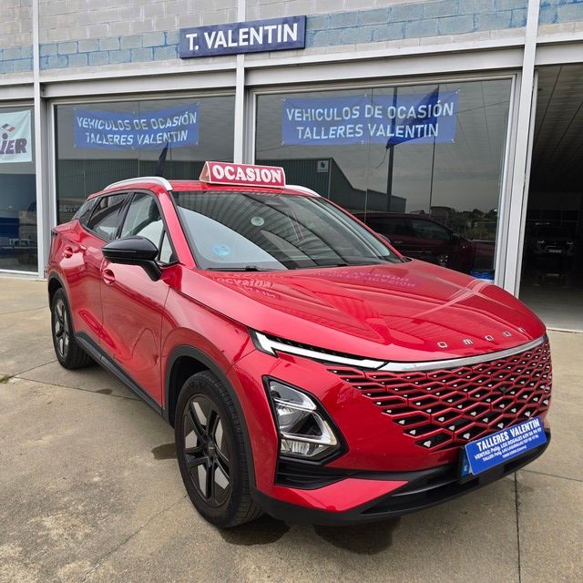 Un coche rojo está aparcado delante de un concesionario de automóviles.