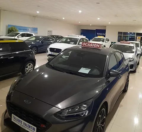 Una fila de coches están aparcados en una sala de exposición.