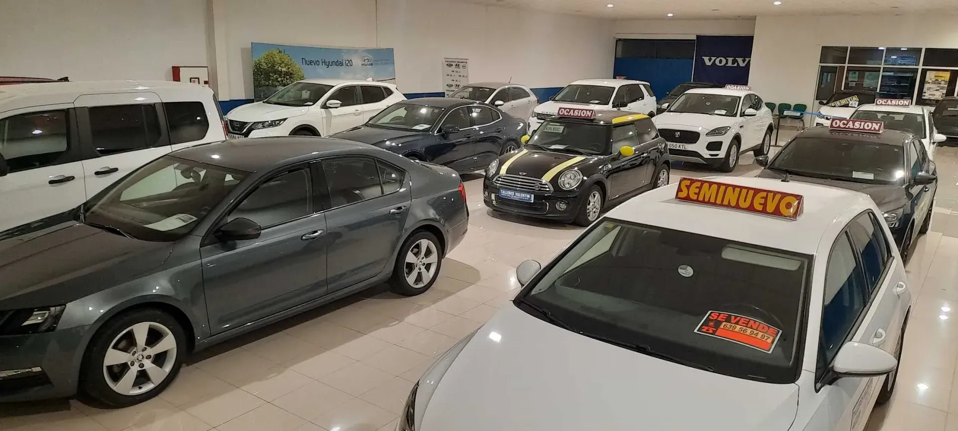 Hay muchos coches aparcados en una sala de exposición.