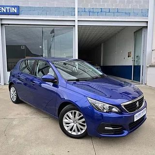 Un coche azul está aparcado delante de un concesionario de automóviles.