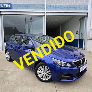 Un coche azul está aparcado delante de un concesionario de automóviles.