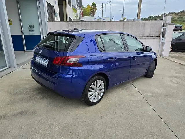 Un coche azul está estacionado en un estacionamiento frente a un edificio.