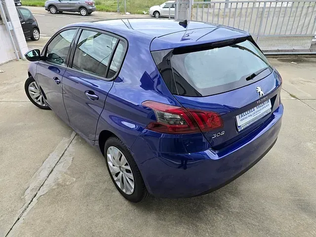Un Peugeot 308 hatchback azul está estacionado en un estacionamiento.
