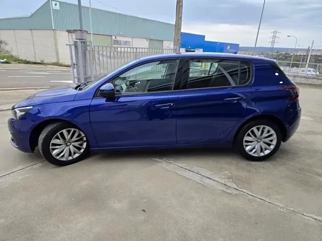 Un coche azul está aparcado en un estacionamiento al lado de un edificio.