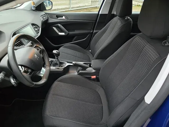El interior de un coche azul con asientos negros y un volante.
