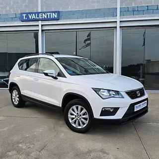 Un coche blanco está aparcado delante de un concesionario de automóviles.