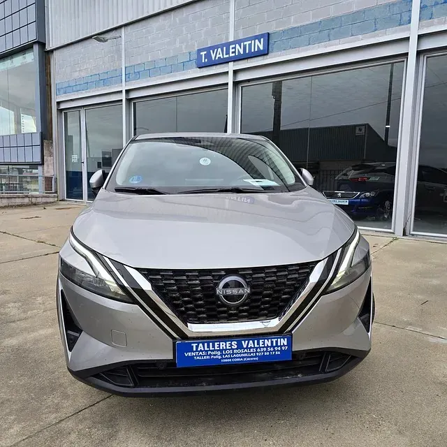 Un Nissan Qashqai está estacionado frente a un concesionario de automóviles.