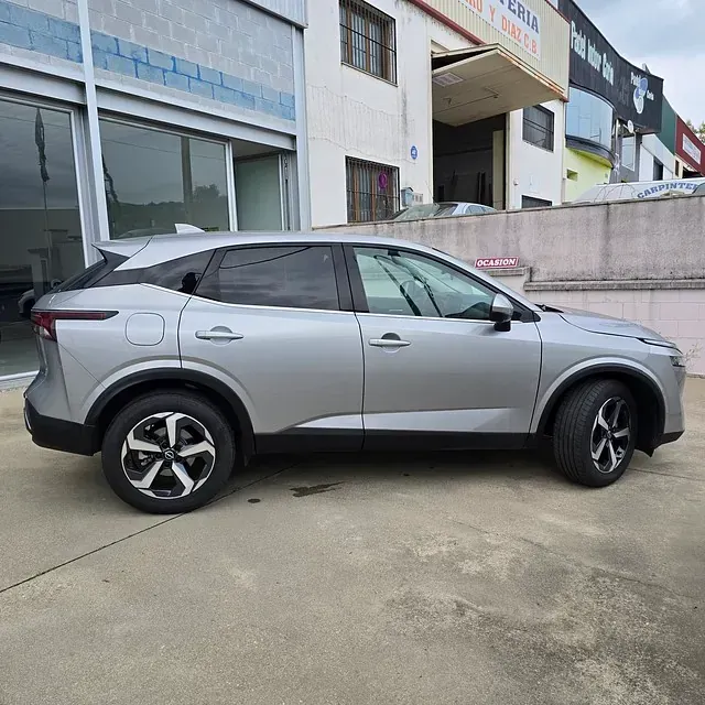 Un coche plateado está aparcado delante de un edificio.