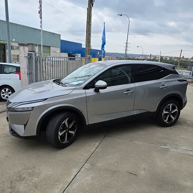 Un coche plateado está aparcado delante de un edificio.