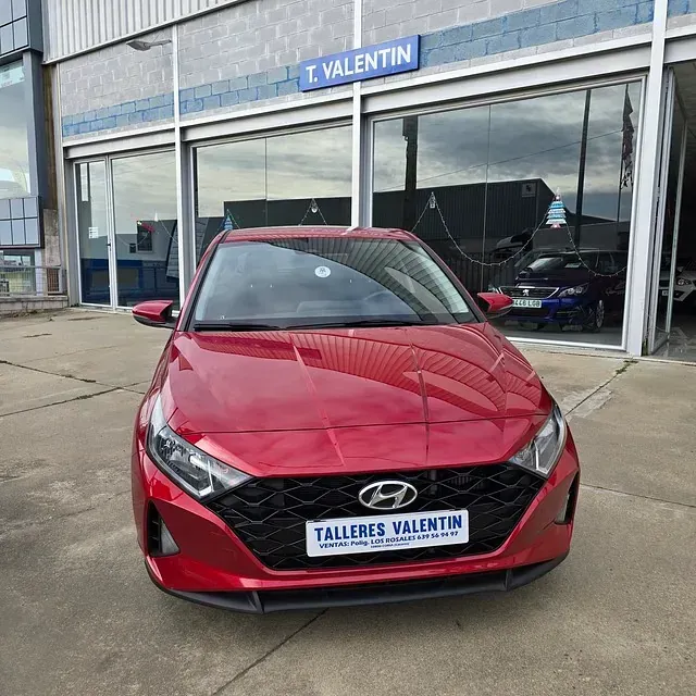 Un coche rojo está aparcado delante de Talleres Valentín.