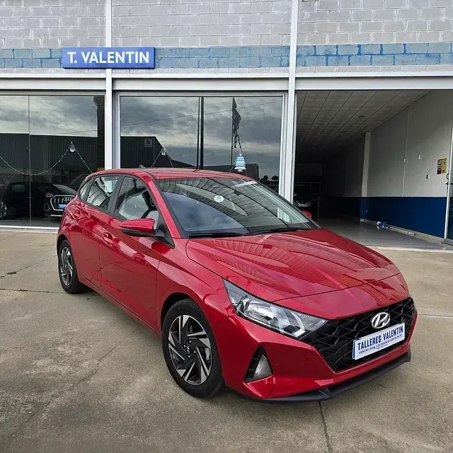 Un coche rojo está aparcado delante de un concesionario de coches T. Valentin.