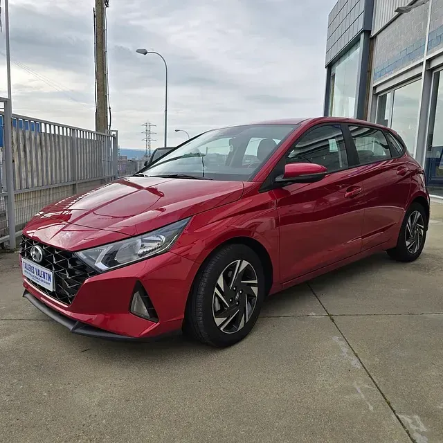 Un coche rojo está aparcado delante de un edificio.